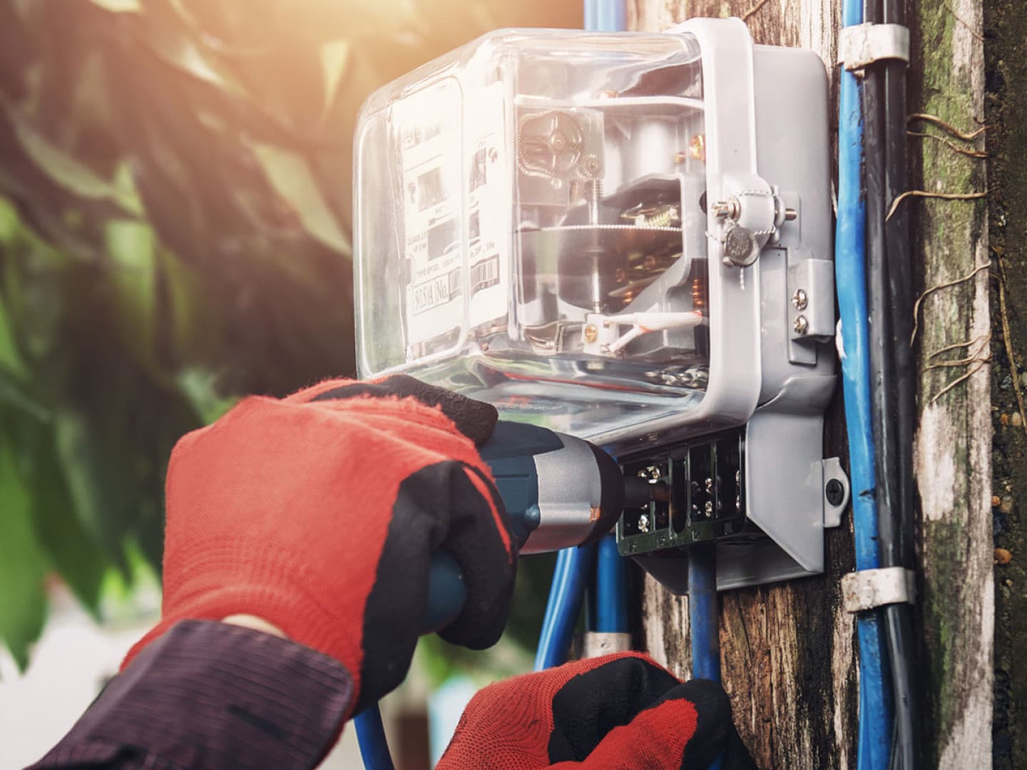 Electrician in work gloves installing an electric meter on a utility pole